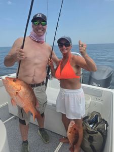 Red snapper fishing success on boat in Orange Beach AL with two anglers displaying their catch