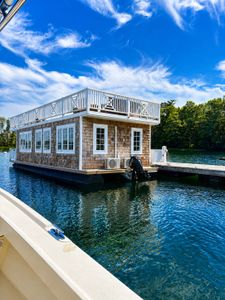 Floating houseboat with wooden shingles and white railings moored at Wells Harbor ME