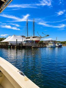 Historic schooner and fishing boats docked at Wells Harbor Maine marina with white buildings