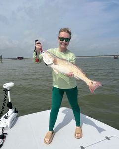 Angler holds large 23-inch fish against the backdrop of Corpus Christi