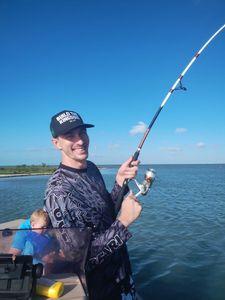 Fishing rod held over blue water in Corpus Christi TX with boat deck visible
