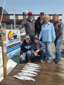 Fishing charter group displaying fresh caught Coho salmon on dock in Port Washington WI