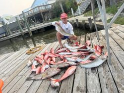 A fisherman holding 2 large fish on Dauphin Island