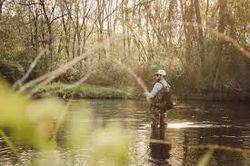 Angler fishing in calm river surrounded by bare winter trees in Florida City FL