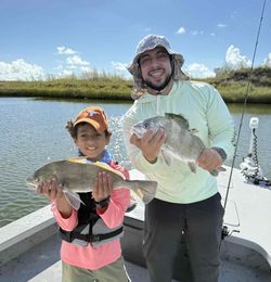Two anglers displaying caught black drum fish on fishing boat in Corpus Christi TX