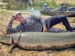 Alligator gar fishing catch in Cayuga TX with boat on shore