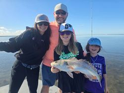 A family enjoying a day of fishing and quality time together by the serene waters, proudly displaying their latest catch.