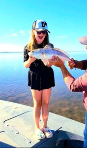 The image captures the excitement of a successful catch as a happy angler proudly displays their prize fish against the serene backdrop of the calm waters and clear blue sky.
