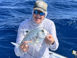 Freshly caught African Pompano being held up during deep sea fishing trip