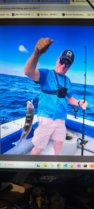 Angler holding caught fish on fishing boat in blue ocean waters