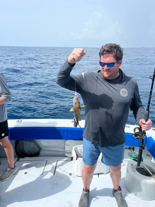 Angler displays caught fish while fishing on boat in open water