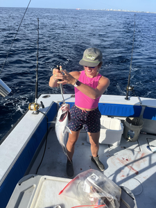 Large fish being held on fishing boat deck with multiple fishing rods visible