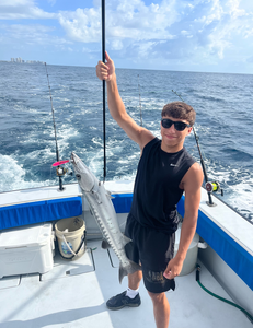Great barracuda caught during deep sea fishing trip displayed on boat deck