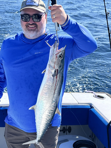 Freshly caught King Mackerel being held up on fishing boat deck over ocean water