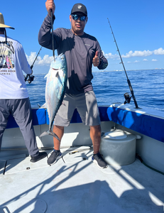 Angler holding freshly caught Little Tunny fish on fishing boat deck
