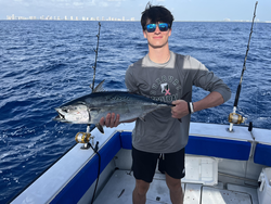 Angler holding fresh caught Little Tunny fish on fishing boat deck
