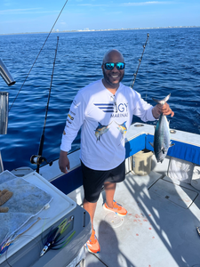 Angler holding freshly caught little tunny fish on fishing boat deck with multiple fishing rods