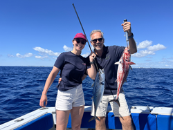 Two anglers displaying their catch of little tunny and another fish species on fishing boat