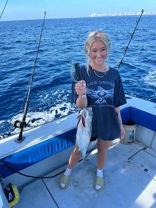 Angler holding fresh caught Little Tunny fish on fishing boat with ocean background