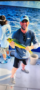 Angler holding fresh caught mahi mahi fish on fishing boat deck over blue ocean water