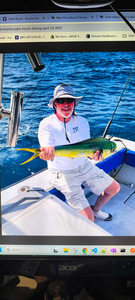Angler holding fresh caught mahi mahi on fishing boat deck over blue ocean water