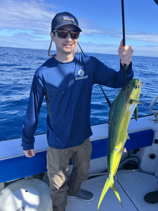 Angler holding caught mahi mahi fish on fishing boat in ocean