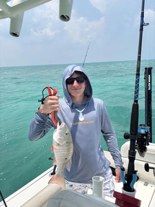 Angler holding freshly caught mutton snapper on fishing boat in ocean waters