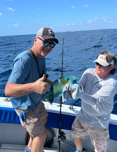 Two anglers on fishing boat holding colorful caught fish over ocean water