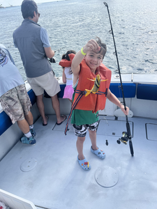 Young angler holding fishing rod on boat deck with porkfish catch