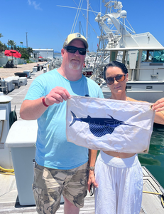 Fishing flag with sailfish design displayed at marina dock with charter boats in background