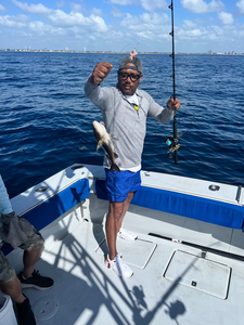 Angler holding caught fish on fishing boat with rod in open water