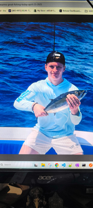Angler holding caught fish on fishing boat in blue ocean water