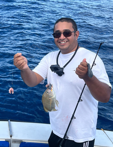 Angler holding caught White Grunt fish on fishing boat over blue ocean water