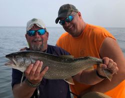 Fisherman holding a lake trout while fishing at Cumberland Head