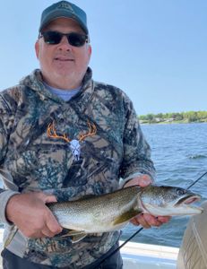 Angler proudly displaying a 15-inch lake trout catch in Peru