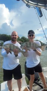 Two anglers with a pair of black drum fish in FL