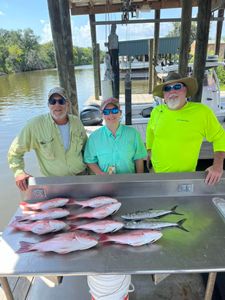 Three happy anglers holding their 18-inch fishing catch in Hopedale