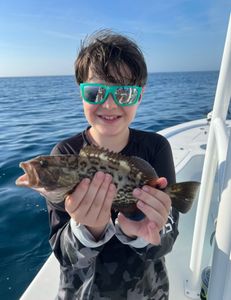 A fisherman holding a large gag grouper caught in Mount Pleasant