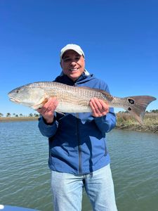 A fisherman holding a large redfish caught in Mount Pleasant