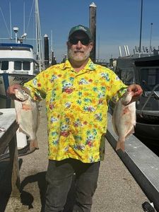 Two fish caught during fishing trip at Reedsport OR marina with boats in background