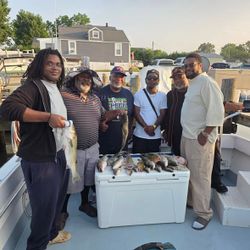 Fishing charter group displaying their catch of fish in cooler on boat deck in Baltimore MD