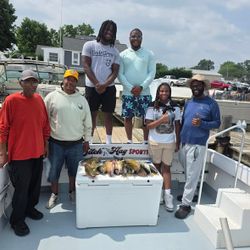 Fishing charter group displaying their catch in cooler on boat deck in Baltimore MD