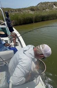 Fishing boat with anglers using net to land catch in Corpus Christi TX waters
