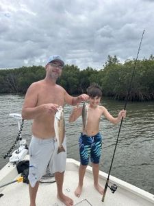 An angler holding a 15-inch fish under a sunny sky in FL
