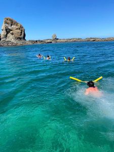 Snorkelers swimming in crystal clear turquoise waters near rocky coastline at Playa Flamingo Guanacaste Province