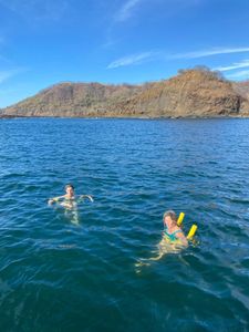 Two people snorkeling in clear blue waters near coastal hills at Playa Flamingo Guanacaste Province