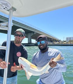 Two anglers displaying a redfish catch on fishing boat in Orange Beach AL
