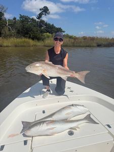 Angler holding large redfish on boat with two additional redfish in Brunswick GA