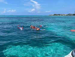 Crystal clear turquoise waters in Nassau with snorkelers floating on the surface, pristine coral reef visible below