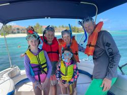 Family snorkeling group on boat in Nassau waters with snorkel gear and life jackets